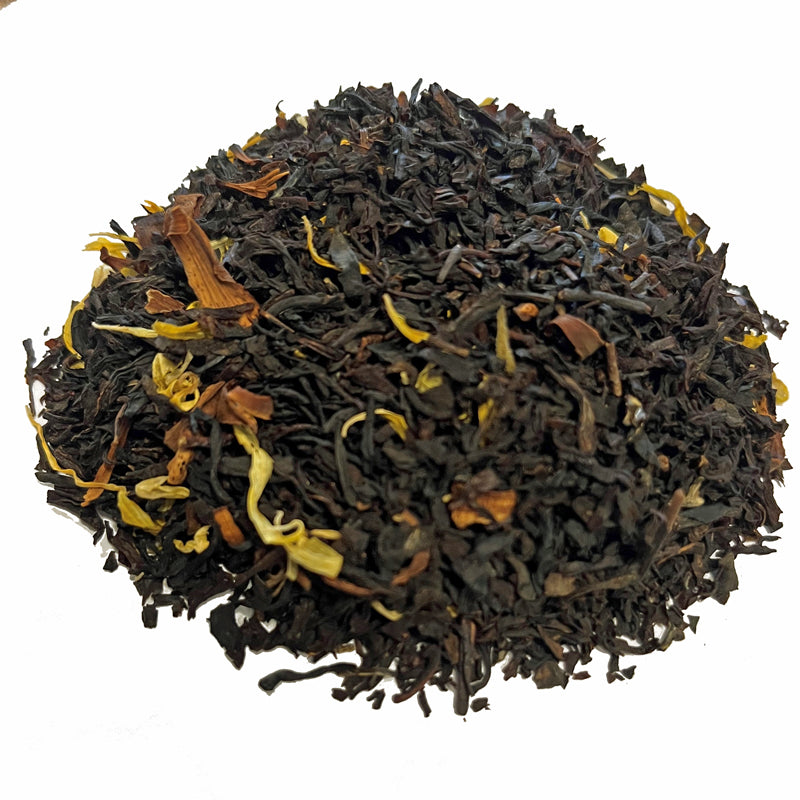 Close-up of black tea leaves with yellow flowers on a white background