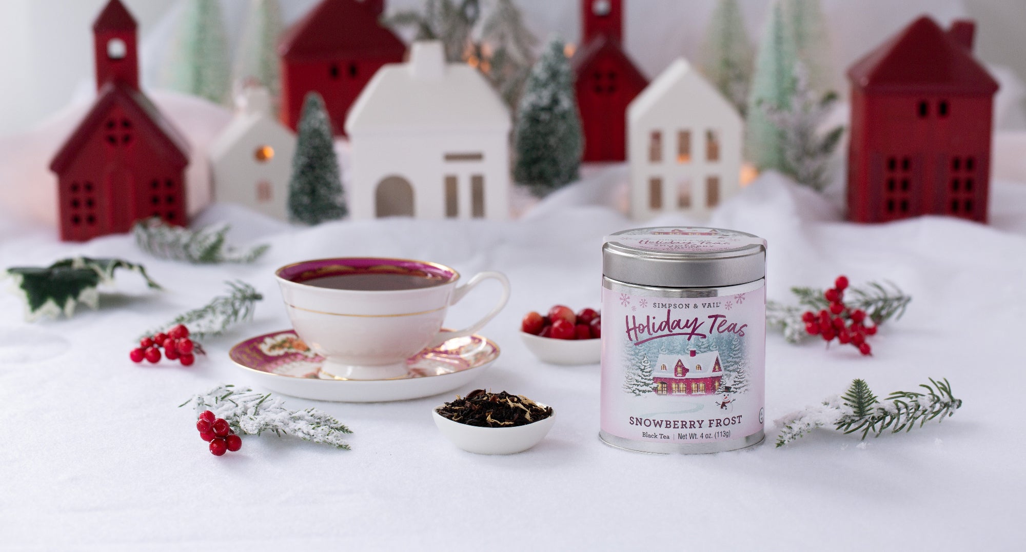 Tea cup with saucer, tea canister labeled 'Holiday Tea', and festive decorations on a white surface.